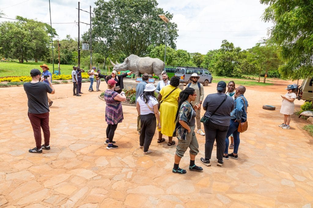 reiseteilnehmer vor dem eingang eines nationalparks mit nashörnern